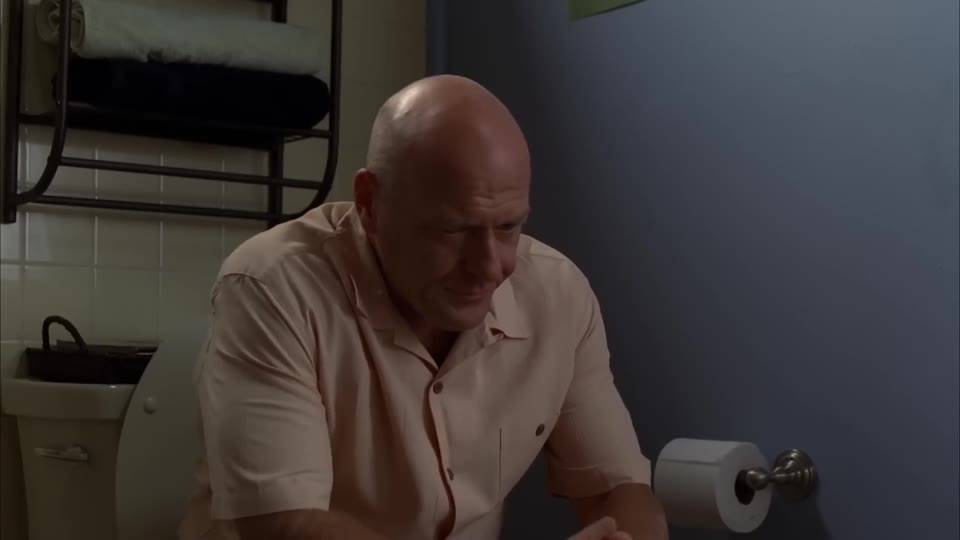 Hank seated, forearms on his thighs, hands empty