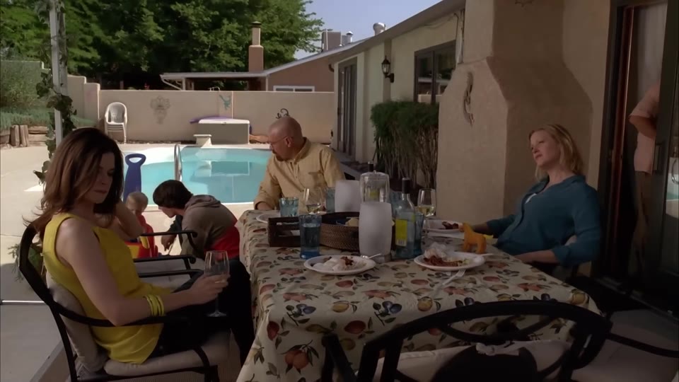 The family at the table beside the pool with Hank’s chair empty